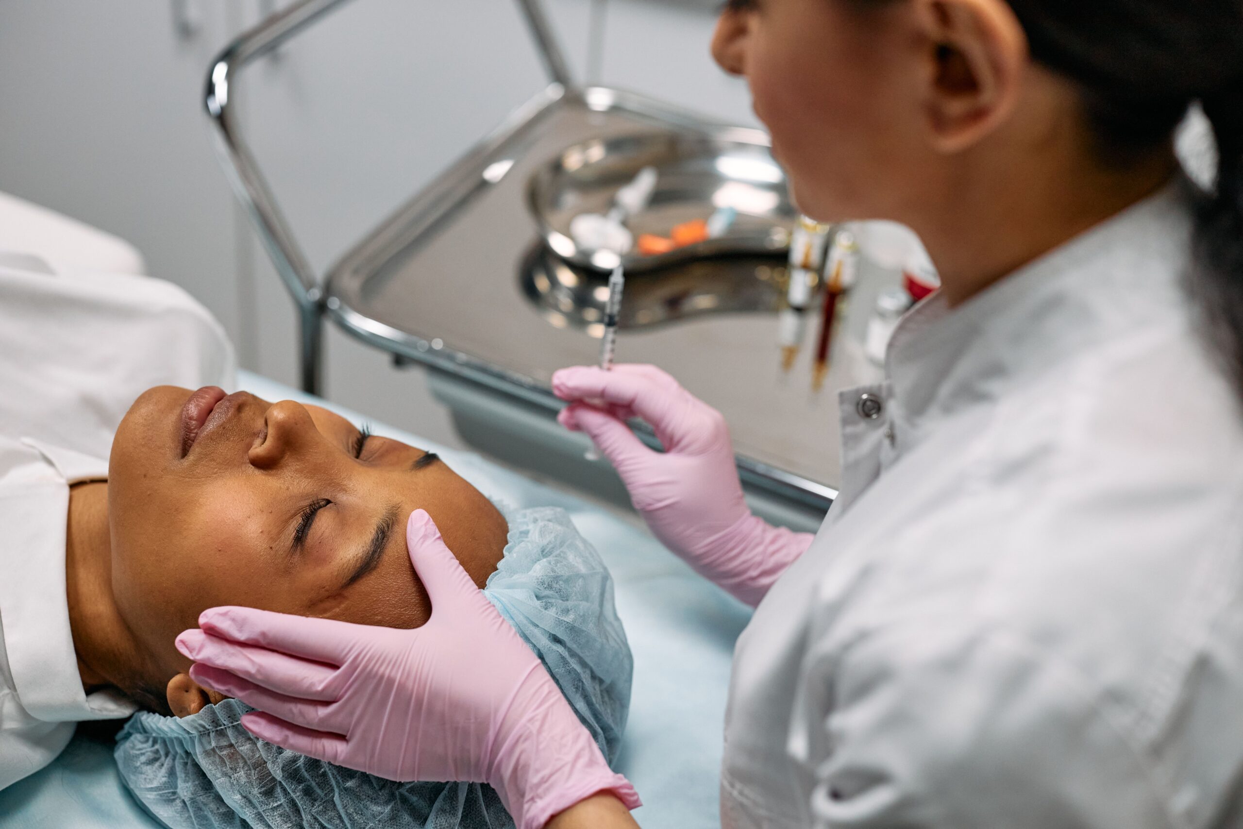 Professional administering skincare treatment with syringe indoors.